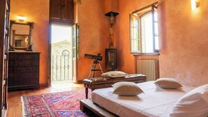 Ein Schlafzimmer mit einem Bett, einer Kommode, einem Teleskop und einem Fenster.