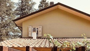 Una casa con techo de tejas, paredes de piedra y contraventanas de madera.