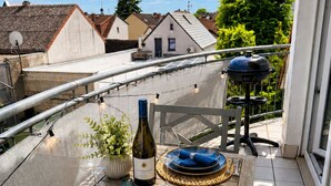 A balcony with a table set for two, a bottle of wine, and a grill. - Velmora Boutique Suites Rheingau - Balcony & Grill (Oestrich-Winkel)