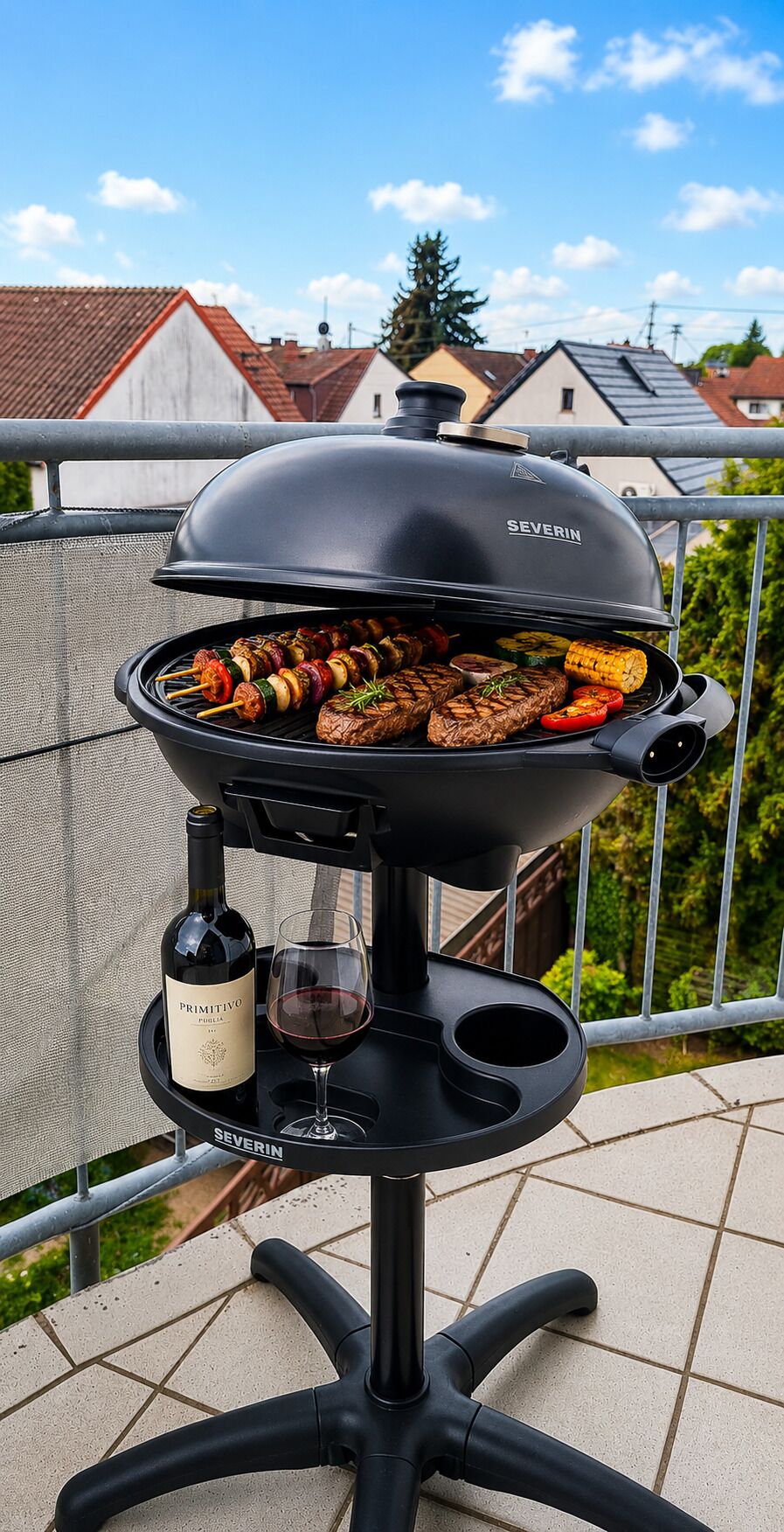 Ein schwarzer Grill mit einer Weinflasche und einem Glas auf einer Terrasse.