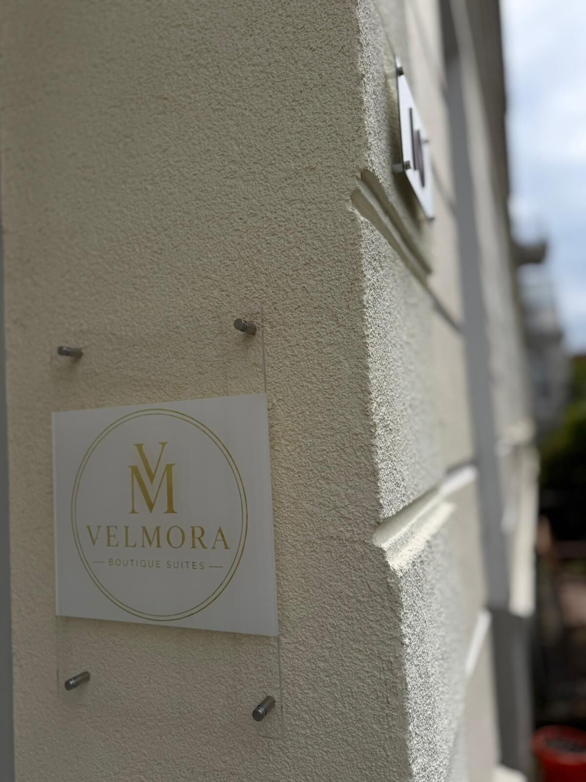 A sign for 'VELMORA Boutique Suites' mounted on a textured wall.