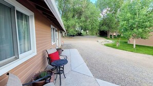Un patio couvert avec des meubles d’extérieur, une allée en gravier et une maison dont le revêtement extérieur est de couleur marron.
