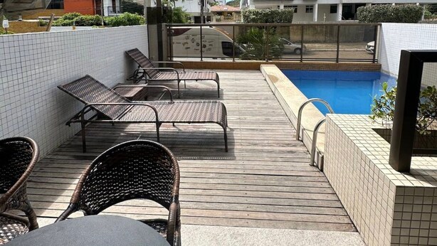 Terraço no telhado com piscina, espreguiçadeiras e vista para os edifícios ao redor.