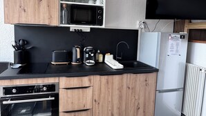 Una cocina moderna con armarios de madera, microondas integrado, refrigerador y tostadora.