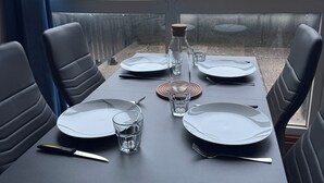 Una mesa de comedor dispuesta con platos, vasos y cubiertos, junto con una botella y un posavasos.