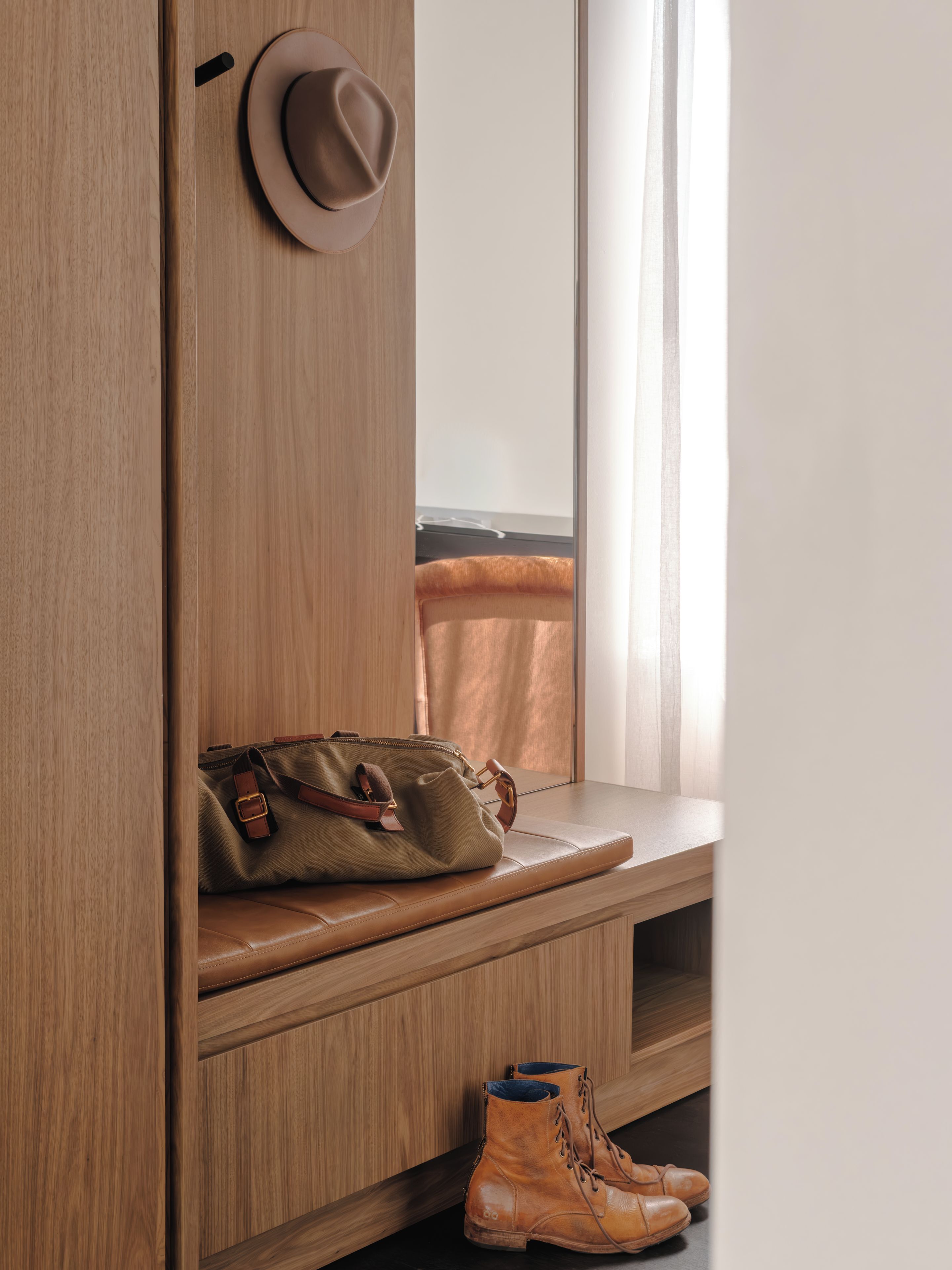 A wooden wardrobe with a mirror, a hat, a handbag, and a pair of boots.