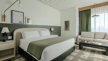 Een hotelkamer met een bed, nachtkastjes, een bank, een salontafel en kunstwerken aan de muur.