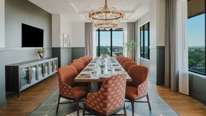 Ein Esszimmer mit einem langen Tisch, der für eine Mahlzeit gedeckt ist, umgeben von Stühlen, mit einem modernen Kronleuchter darüber.