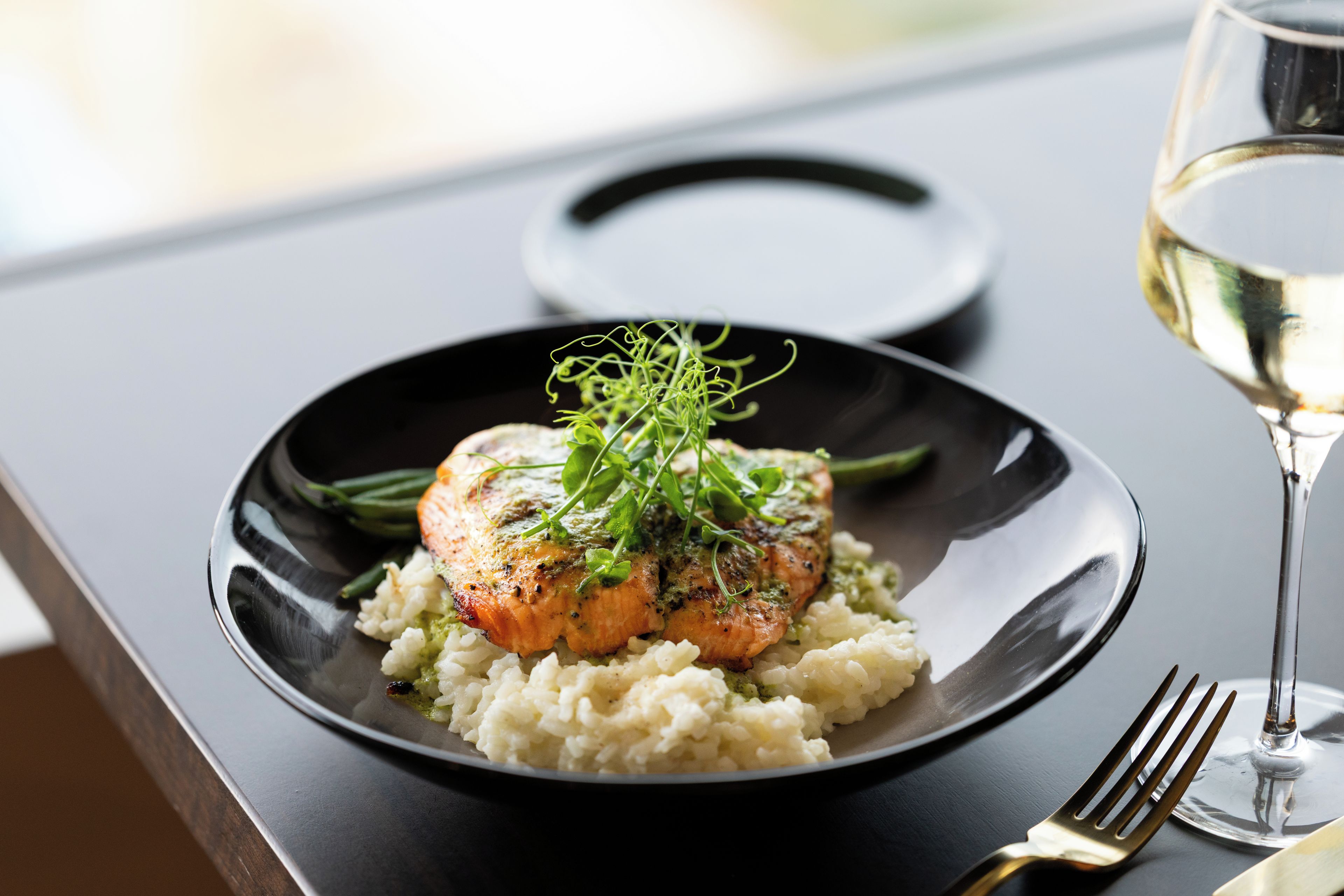 Prato de comida com filé de peixe, acompanhamento verde e arroz.