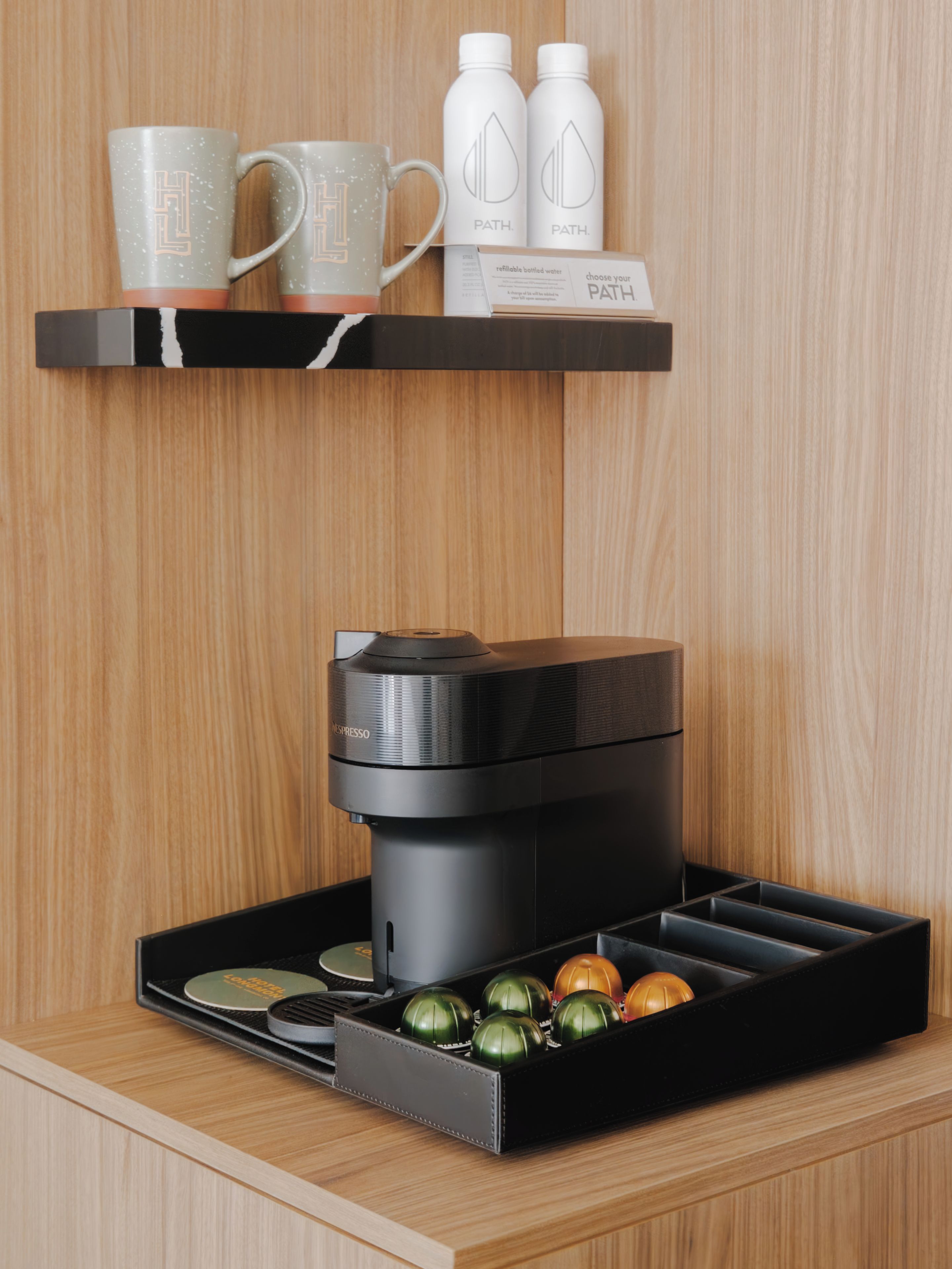 A coffee machine with a tray of coffee pods and a box of coffee capsules on a wooden surface.