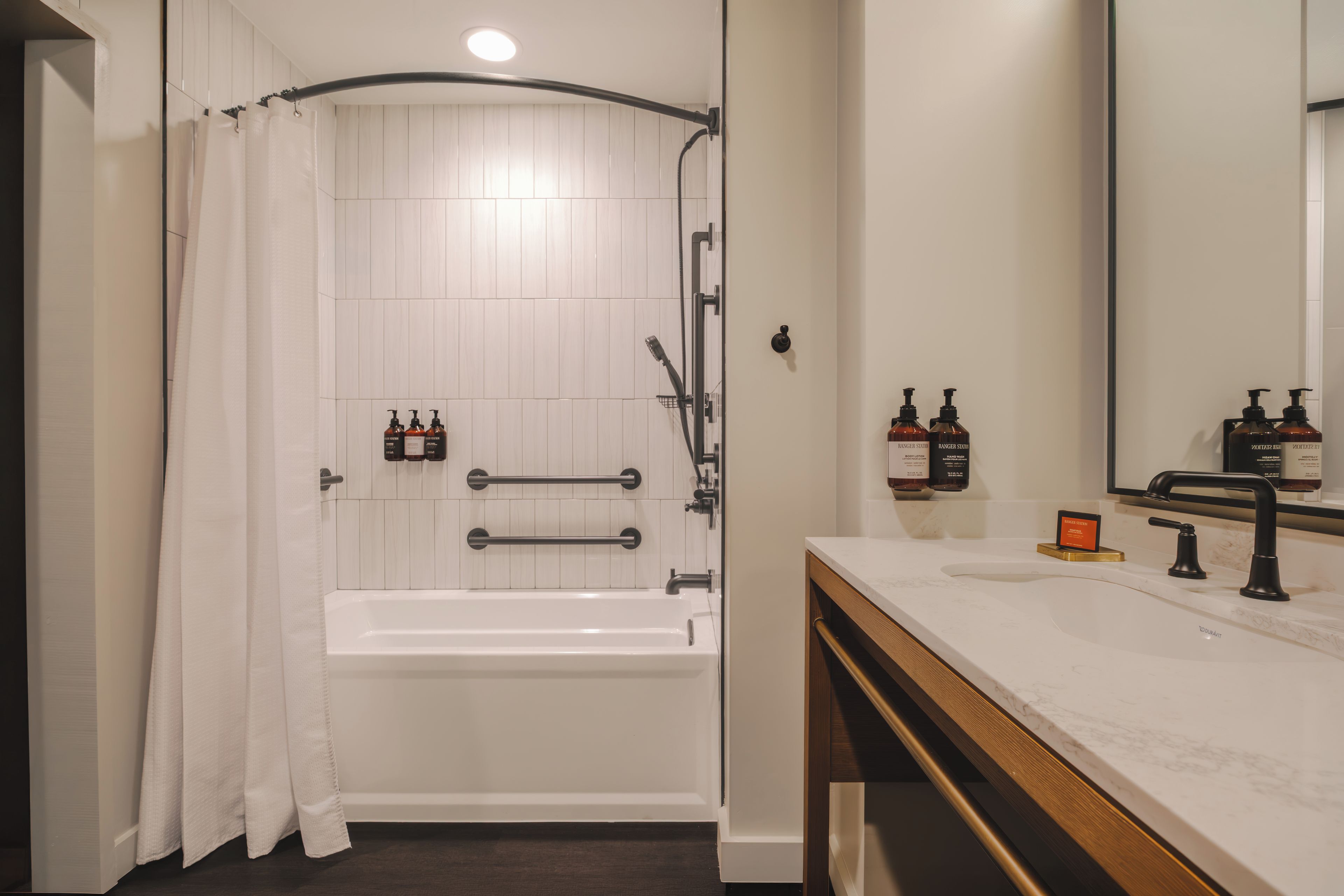 A bathroom with a bathtub, a shower, a vanity with a mirror, and toiletries.