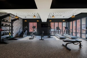 Un gimnasio con cintas de correr, una bicicleta estática y una máquina de pesas.