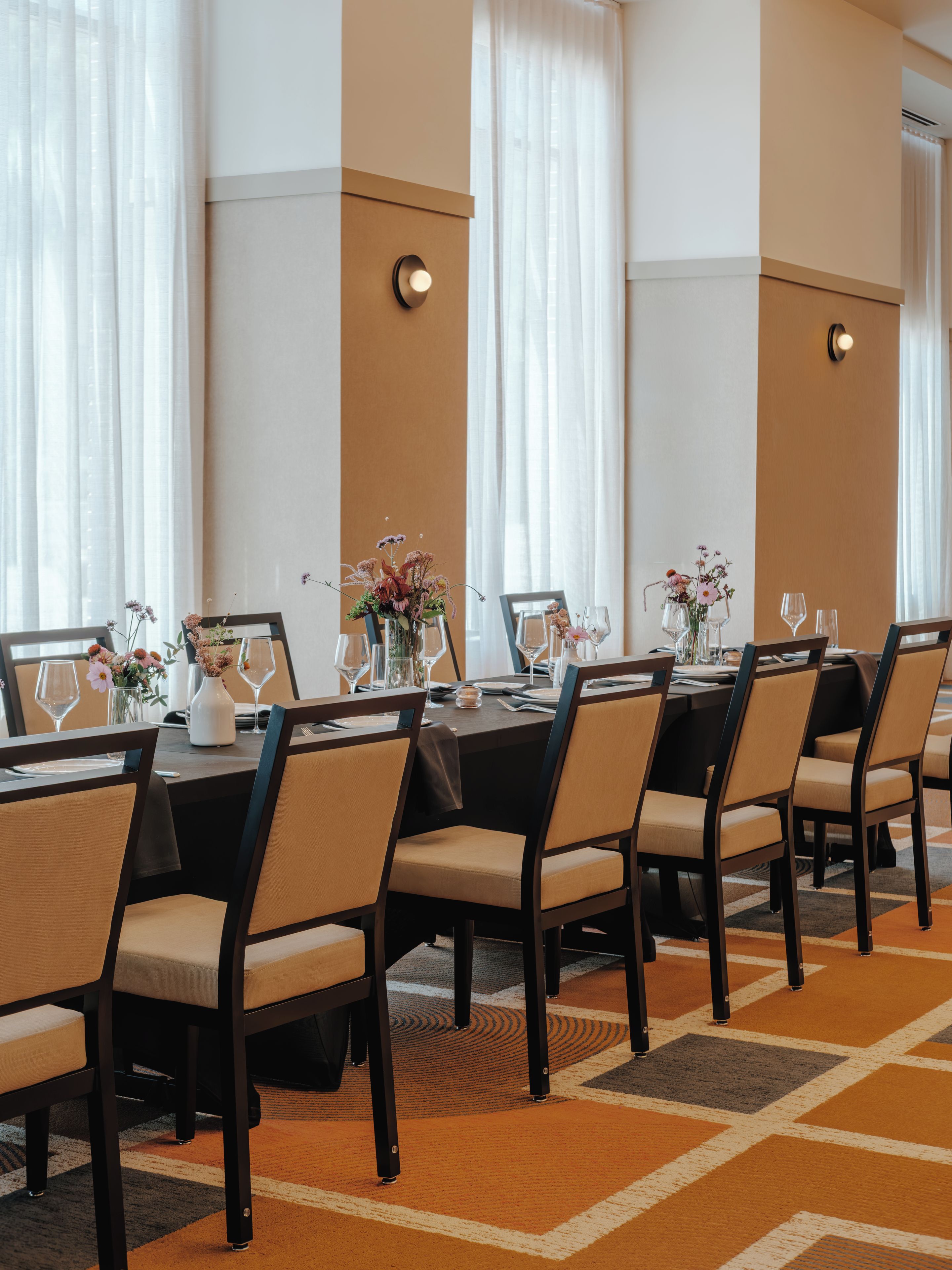 Ein Konferenzraum mit einem langen Tisch, Stühlen und floralen Tischdekorationen.
