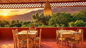 An outdoor dining area with wicker furniture and a view of a mountainous landscape.