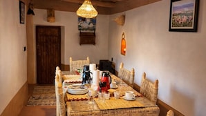 A dining area with a rustic wooden ceiling, woven chairs, a woven tablecloth, and a traditional woven lamp. - DAR DANI café restaurant (Ait Sedrate Jbel El Soufla)