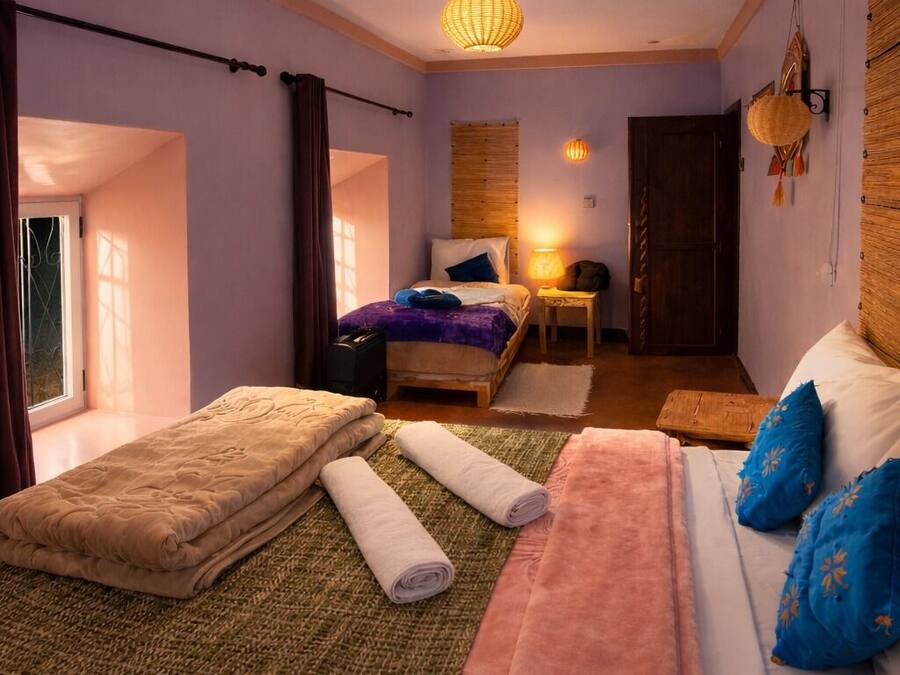 Un dormitorio con cama, mesita de noche, lámpara y ventana.