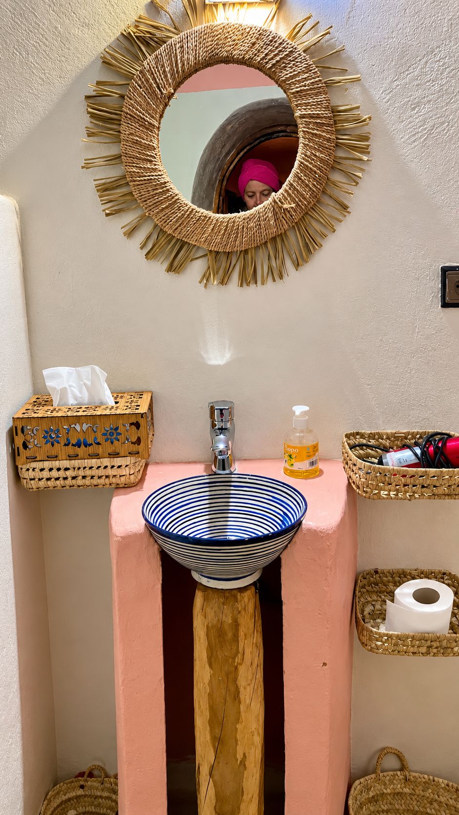 Ein Badezimmer mit einem runden Spiegel, einem Becken mit Streifenmuster und Korbwannen.