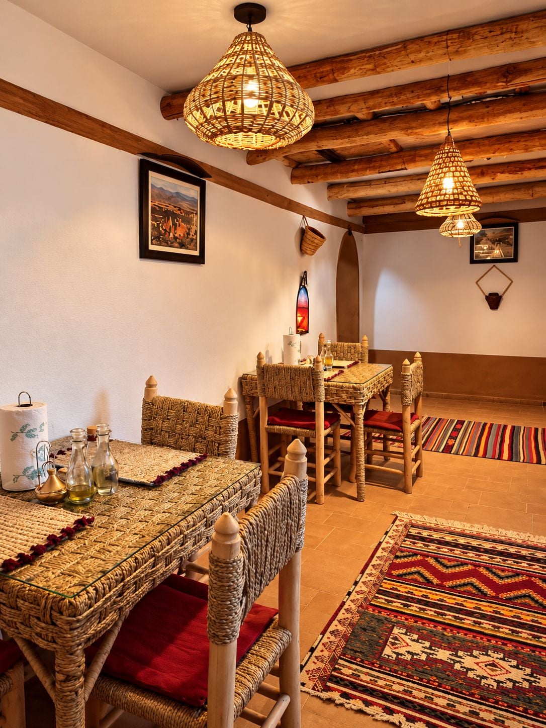 Una habitación tradicional con vigas de madera a la vista, mobiliario tejido y alfombras estampadas.