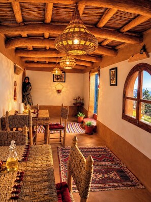 A rustic interior with a high ceiling, woven furniture, and a view through a window.