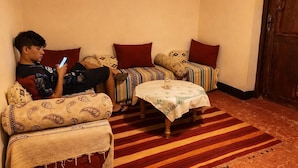 A living room with a sofa, a coffee table, and a patterned rug. - DAR DANI café restaurant (Ait Sedrate Jbel El Soufla)