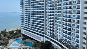Um hotel moderno com várias varandas, piscina e vista para o oceano.