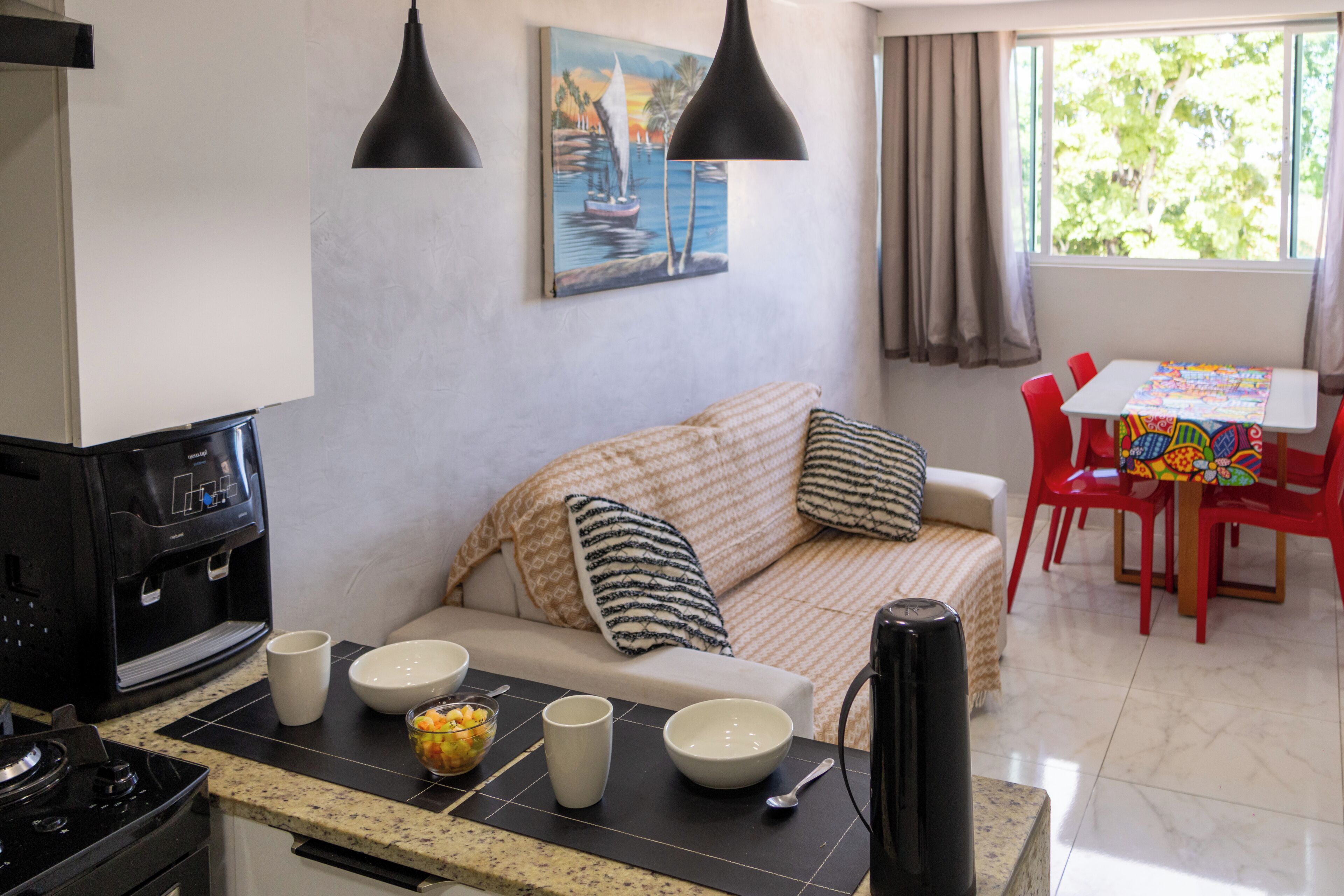 A kitchen with a stove, coffee maker, and dining area with a table and chairs.