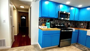 Una cucina moderna con mobili blu, un piano cottura in acciaio inossidabile e una parete di fondo rivestita di piastrelle.