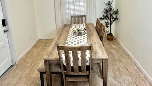 Un comedor con una mesa de madera, sillas, una araña y una planta en maceta.