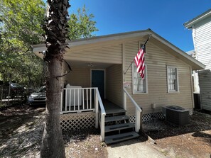 Ein kleines Haus mit Veranda, Überwachungskamera und einer amerikanischen Flagge.
