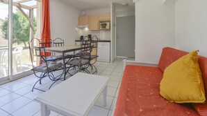 A compact living space with a dining area, kitchenette, and a sofa with a cushion. - Country Stay for 6 in Provence Vineyards (Saint-Saturnin-les-Avignon)
