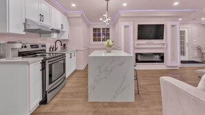 A modern kitchen with white cabinetry, a central island, and a built-in TV.
