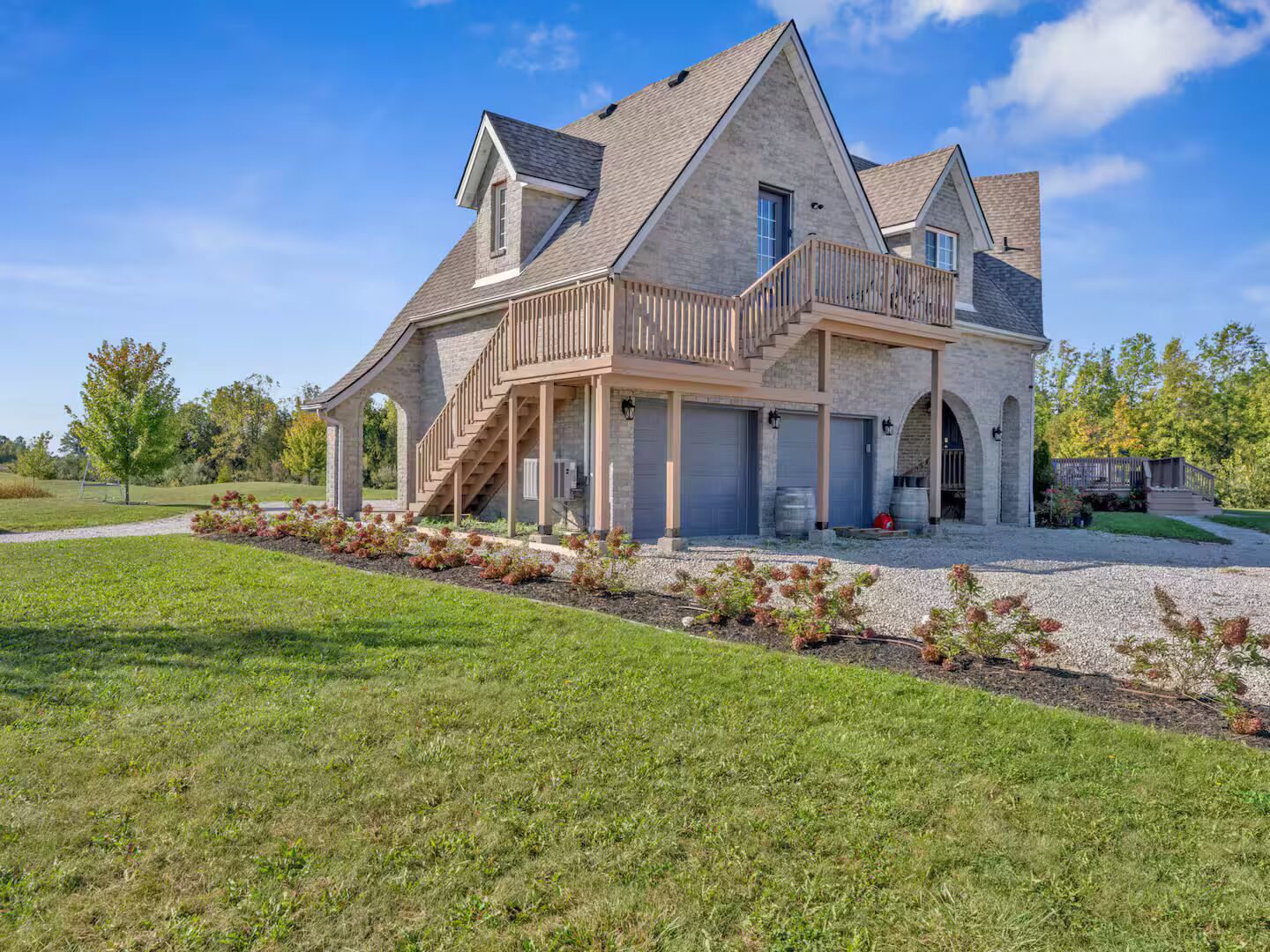 A large, two-story house with a stone facade, a balcony, and a covered porch area.