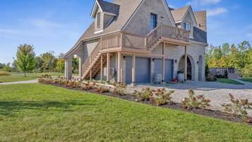 A large, two-story house with a stone facade, a balcony, and a covered porch area.