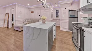 A spacious kitchen with a marble island, modern appliances, and a pendant light.