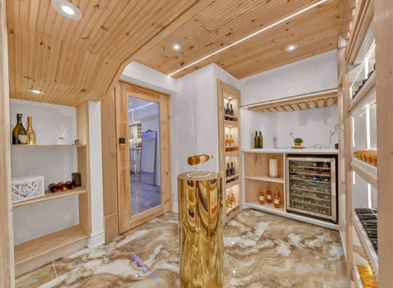 Un interior moderno con techo de madera, piso de mármol y estantes con botellas.