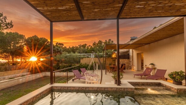Un espace piscine avec une eau cristalline, des chaises longues et une vue imprenable sur le coucher de soleil.