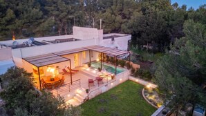 Une maison moderne dotée d’une piscine sur le toit, d’un espace salon extérieur et d’un jardin bien entretenu.