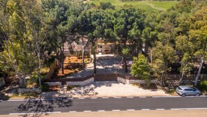 Une propriété située sur la côte, dotée d’une allée pavée, d’arbres et offrant une vue sur la mer.