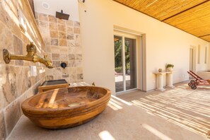 A spa area with a wooden basin, stone walls, and a sliding glass door leading outside. - Villa Essenza Di Pace - Nardò (Nardò)