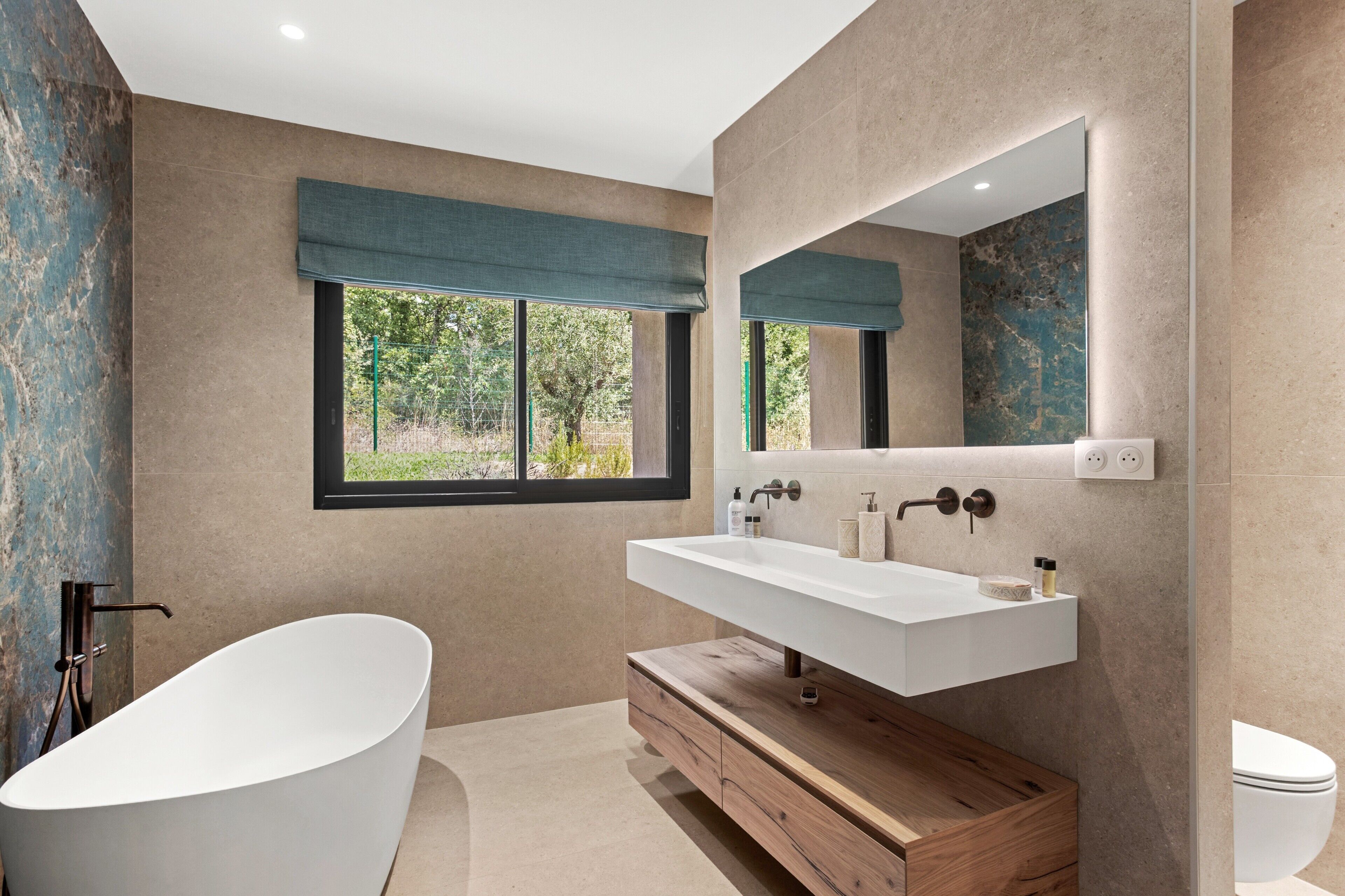 Un bagno moderno con una vasca da bagno indipendente, un mobile lavabo con specchio e un water.