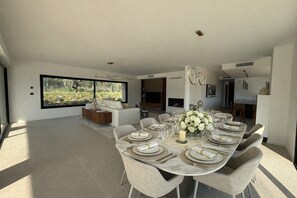 A modern dining room with a large table set for six, a sofa, and a TV in the background. - Prestige at “Villa Augusta” Golf & SPA Terre Blanche in Tourrettes (Tourrettes)