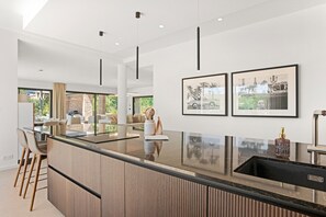 A modern kitchen with a central island, pendant lighting, and framed artwork on the wall.