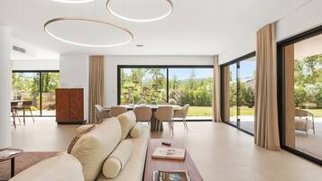 Un salon moderne avec un canapé, un coin repas et de grandes fenêtres.