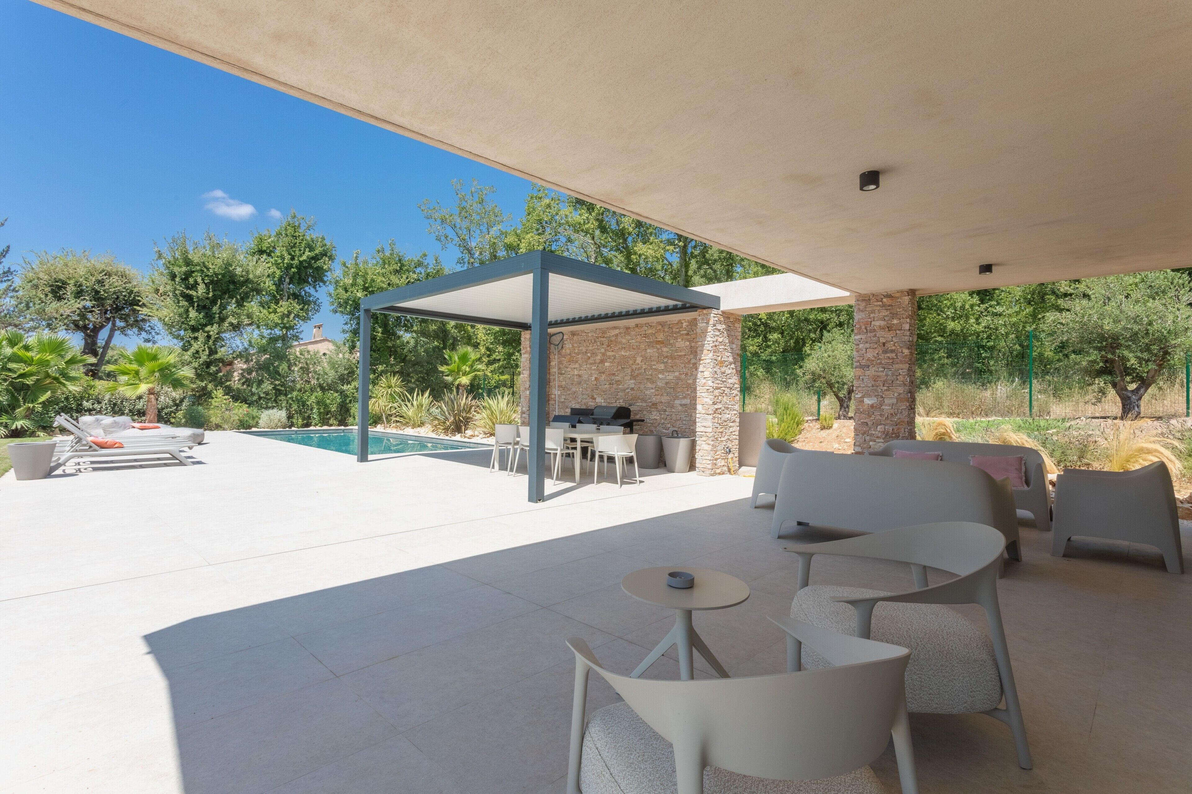 An outdoor patio area with a pool, seating, and a pergola structure.