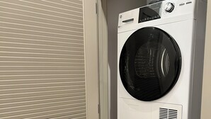 A stacked washer and dryer unit in a utility room. - Brick & Bed - Riverfront Loft - 405 (St. Louis)