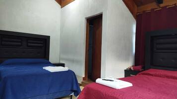 A room with two beds, a wooden ceiling, and a door leading to another room.