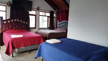 Habitación con dos camas, vigas de madera en el techo y una ventana con cortinas.