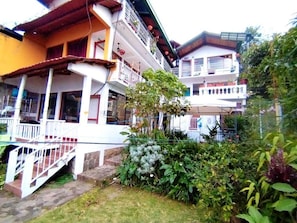 A multi-story building with balconies, a covered porch, and a garden area. - Hotel Victoria Atitlan (San Pedro La Laguna)