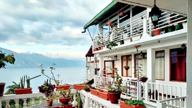 Un hotel con un balcone, piante in vaso e vista sull'acqua.