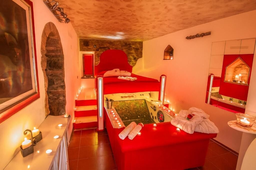 A red spa room with a massage table, candles, and a small window.